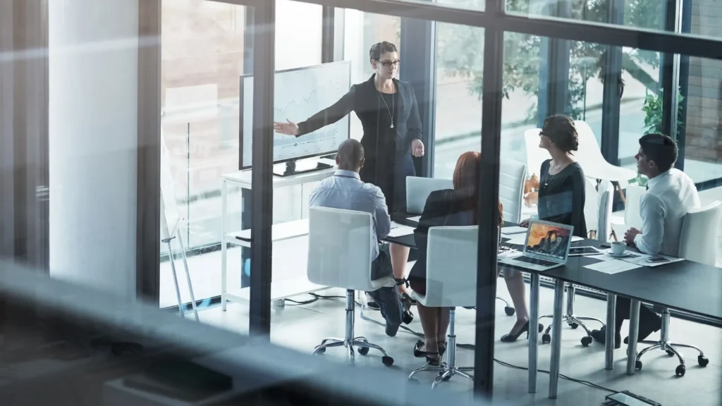A woman in corporate attire is onboarding new vendors in the boardroom.